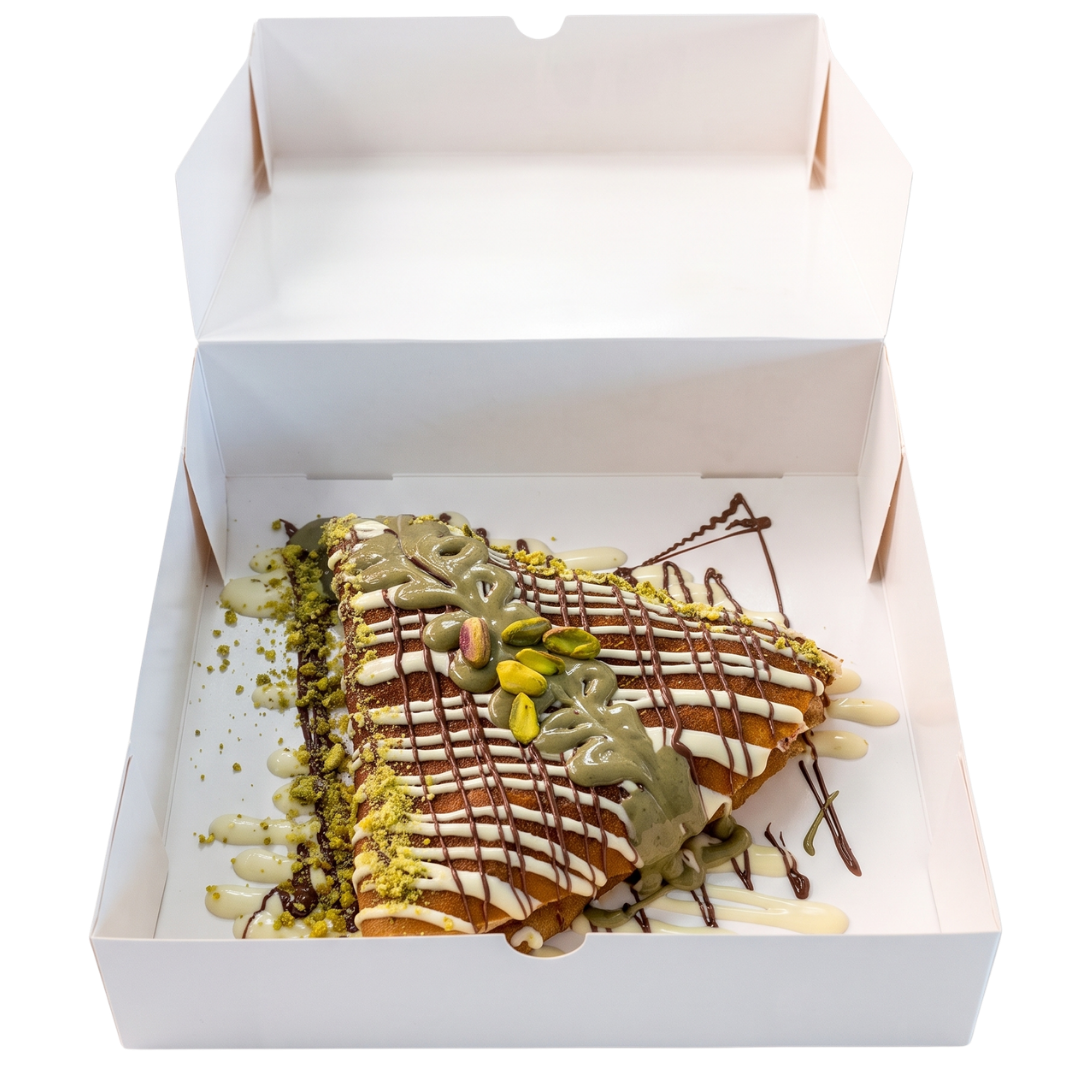 Signature crêpe with pistachio and chocolate drizzle in an open box