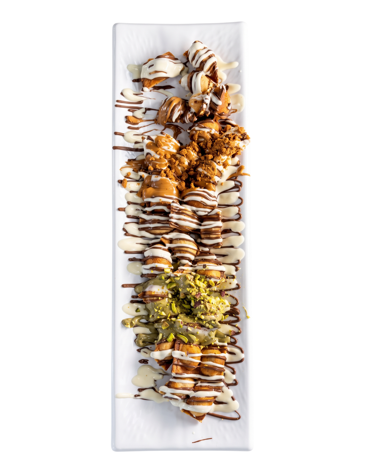 Long plate of golden bites drizzled with milk and white chocolate, biscoff crumbs and pistachio